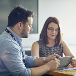 Man and woman sitting at a table looking at an iPad