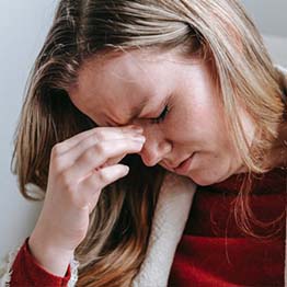 A woman clutching her eyes in pain