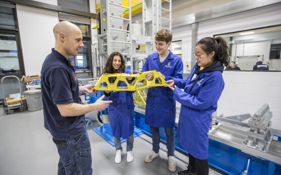 Three students and a lecturer. They are holding a scientific model and wearing lab coats. 