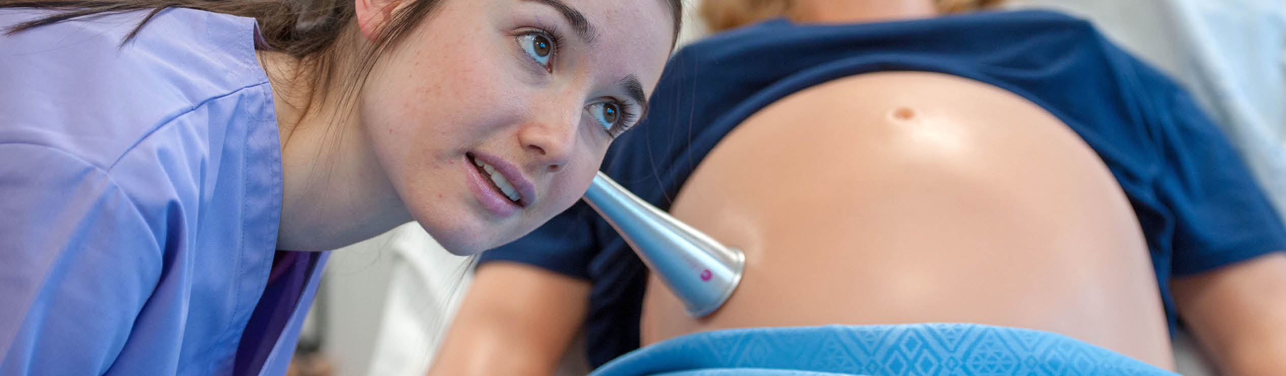 Midwifery student demonstrating on a midwifery dummy