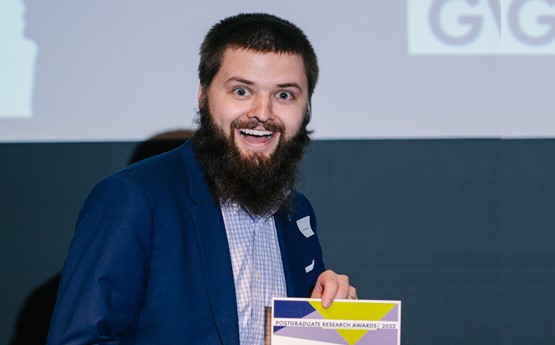 Man with beard looking excited holding a certificate