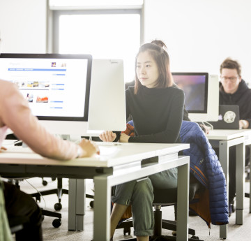 Several students, studying at computers in the library.