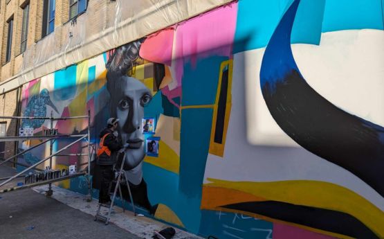 Image of local artist, Hasan Kamil, creating a mural at Bay Campus