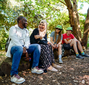 Four students sitting together in woodland